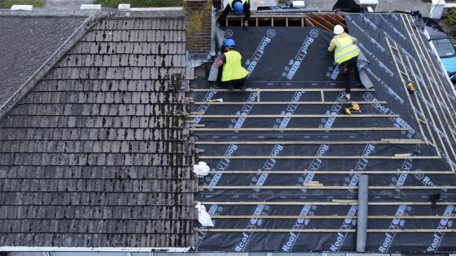 Roofers re-felting a pitched roof