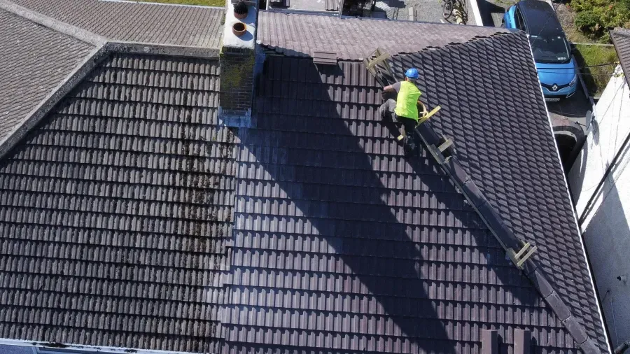 Two roofers working on a tiled roof